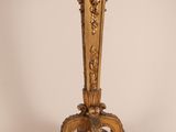 un vase doré posé sur un socle, sur fond blanc