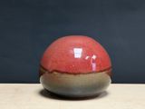 un vase rouge et marron posé sur une table en bois