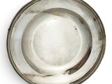 une assiette ancienne en argent, avec un bord perlé sur un fond blanc