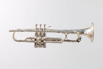 an old silver trumpet sitting on top of a white surface