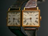 two watches that are sitting side by side on a table