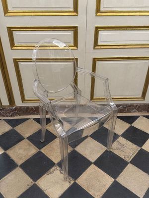 une chaise en plastique transparent posée sur un sol à carreaux