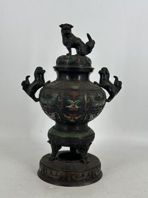 une image représentant un vase en bronze surmonté d'un oiseau