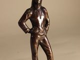 bronze statue of a woman standing on a base with her hands on her hips