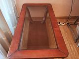 une table en bois avec un plateau en verre, posée sur un parquet en bois massif