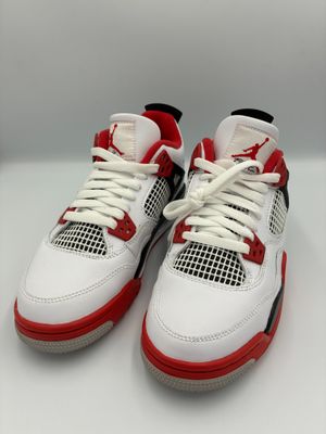 a pair of white and red sneakers on a white surface