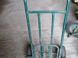 un diable vert muni d'une poignée métallique, dans un garage