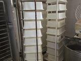 many trays of food stacked on a rack in a kitchen