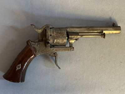un vieux revolver avec une poignée en bois sur une surface blanche