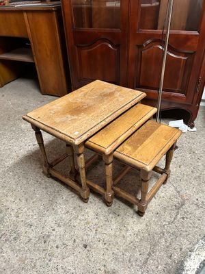 trois tables en bois posées sur un sol en béton, à côté d'une armoire