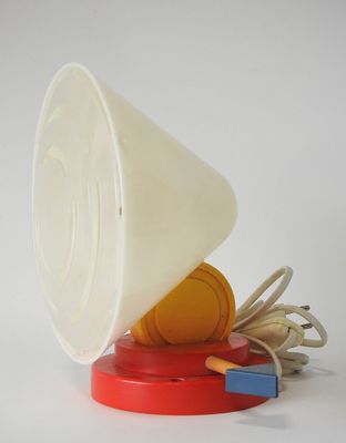 une tasse blanche avec un couvercle rouge posée sur un objet rouge