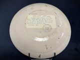 a white plate with writing on it sitting on a stand