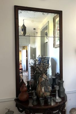 un miroir accroché au mur au-dessus d'une table sur laquelle sont posés des vases