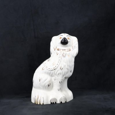 une statue de chien blanc posée sur une surface noire