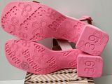 the pink shoes are sitting on top of a brown and white box