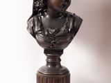 a bronze bust of a woman with a hat on a pedestal