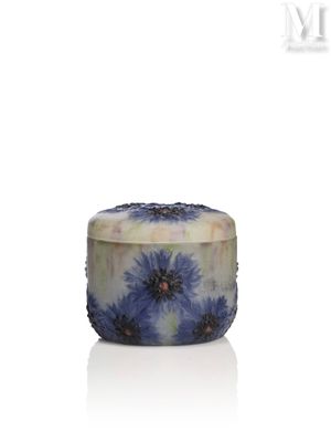 La bougie est ornée d'une fleur bleue et repose sur une surface blanche.
