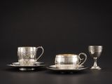 deux tasses et soucoupes argentées posées sur un fond noir