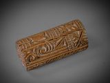 une vieille boîte sculptée, dont la surface grise est ornée de motifs sculptés