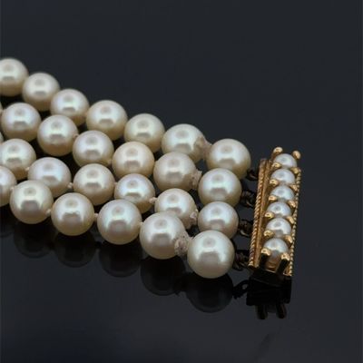 collier de perles avec un fermoir en or sur un fond noir