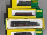 trois boîtes contenant des trains miniatures posées sur une table