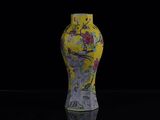 un vase jaune orné de fleurs, posé sur une surface noire