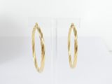 a close up of a pair of gold hoop earrings on a clear stand