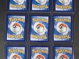 six packs of pokemon trading cards in plastic cases on a table