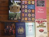 several books on a wooden table with a bottle of wine in front of them