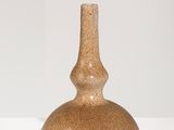 un vase marron posé sur une étagère blanche, sur fond blanc