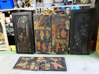 trois portes en bois noires ornées de dessins, posées par terre