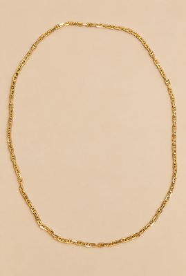 un collier à chaîne en or sur fond beige
