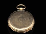 a close up of a gold pocket watch on a black surface