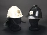 pair of black and white fire helmets on display against a gray background