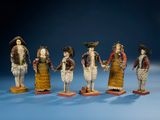 several figurines of people dressed in traditional clothing stand in a row