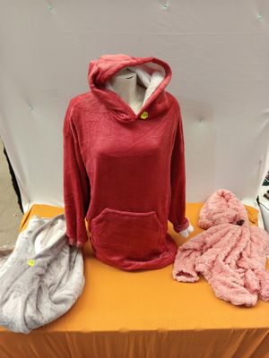 un sweat à capuche rouge posé sur une table où se trouvent d'autres vêtements