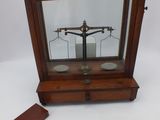 une image représentant une balance avec un socle en bois et une vitre de protection
