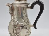 an antique silver coffee pot with a black handle on a stand