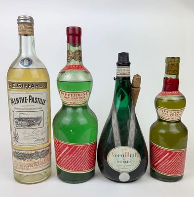 trois bouteilles d'alcool sont alignées sur une surface blanche