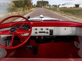 dashboard of a red and white classic car driving down a country road