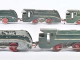 quatre petits trains miniatures posés sur une surface blanche
