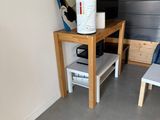 a small table with a coffee pot on it and a chair in front of it