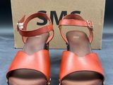 une paire de sandales marron et orange, avec une boîte en arrière-plan