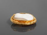 a close up of a gold plated broochle with a white stone