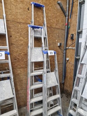 Plusieurs échelles sont empilées contre un mur dans une pièce.