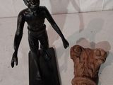 une petite statue représentant un garçon debout à côté d'une statue représentant un homme