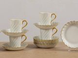 a group of white and gold cups and saucers on a table