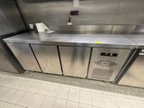 un plan de travail en acier inoxydable dans une cuisine professionnelle, équipé d'un distributeur de papier