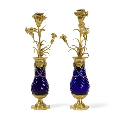 une paire de vases bleus et dorés contenant des fleurs, sur fond blanc