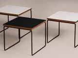 three small tables with black and white tops sit side by side on a plain surface